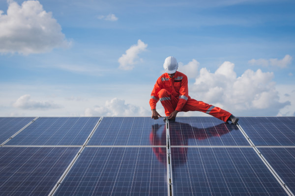 Construction worker standing on installed solar panels with sky in background