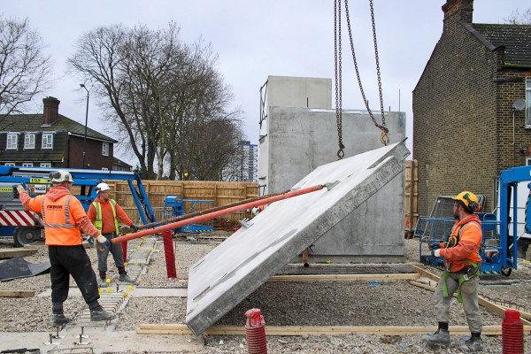Milbank employees use crane lift to stand up precast concrete wall for stair cores installation