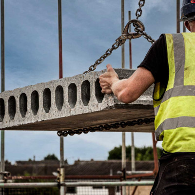 close up of installation fixer holding hollowcore flooring slab supported by crane