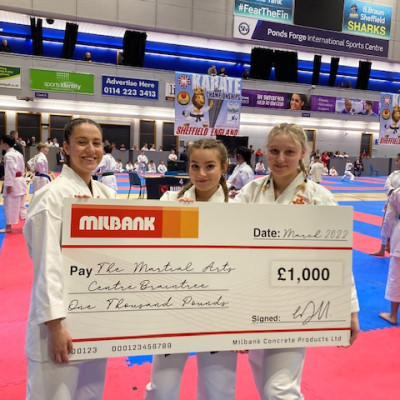 3 girls pose with large cheque donated by milbank concrete products to Braintree martial arts centre