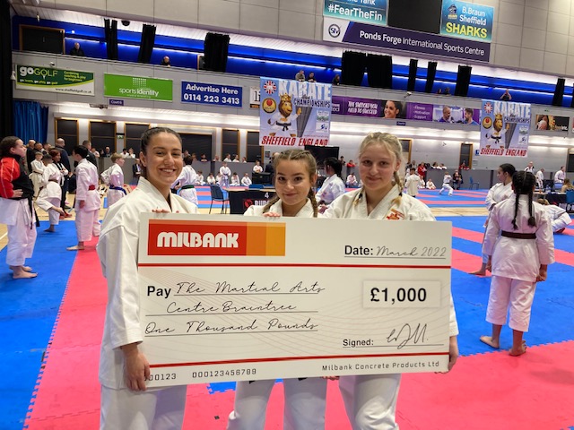 3 girls pose with large cheque donated by milbank concrete products to Braintree martial arts centre