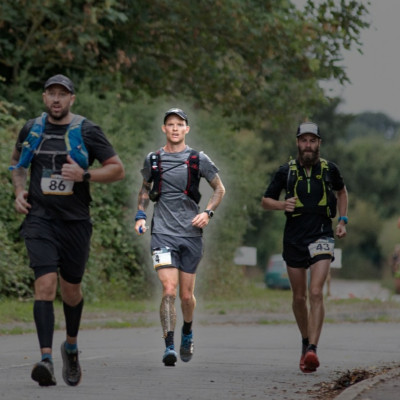 3 men run down a road, the middle man is highlighted