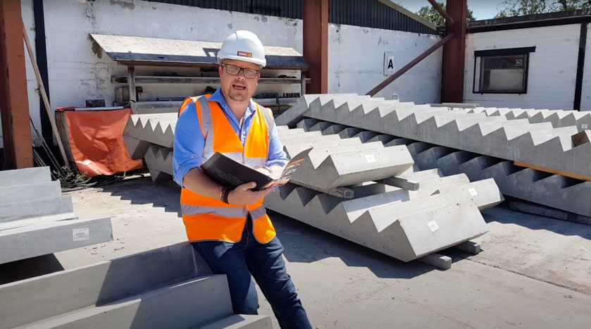 Mark Ellis poses with book in front of precast concrete stair units