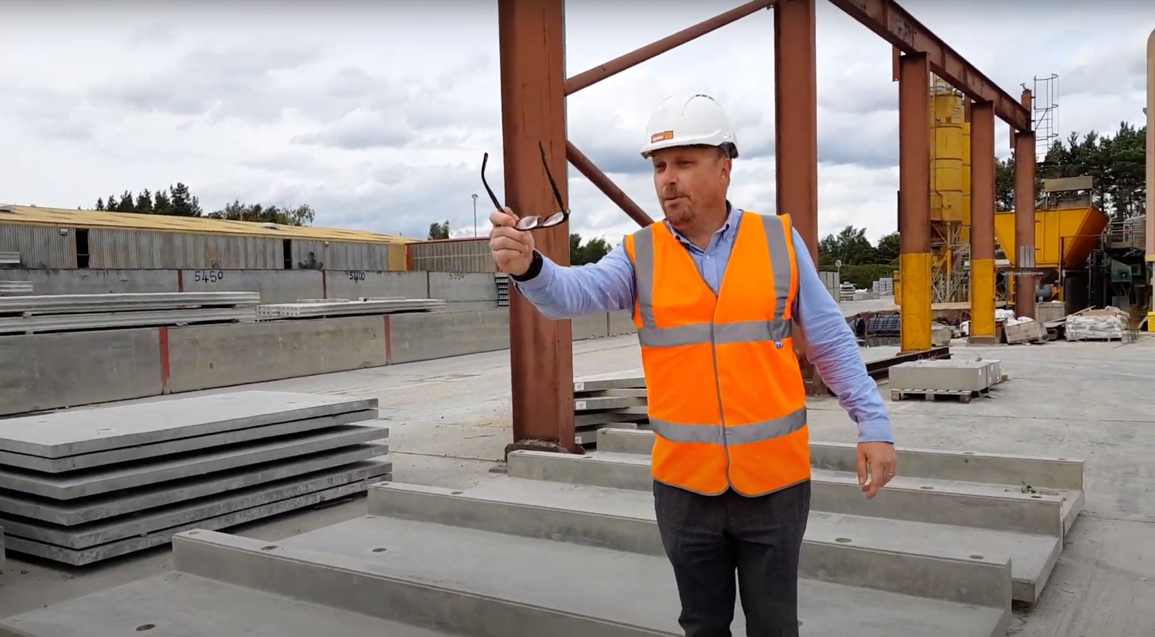 Mark Ellis holds glasses whilst standing on precast concrete stadium units