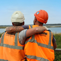 Two Milbank employees stand side by side with their arms around each other