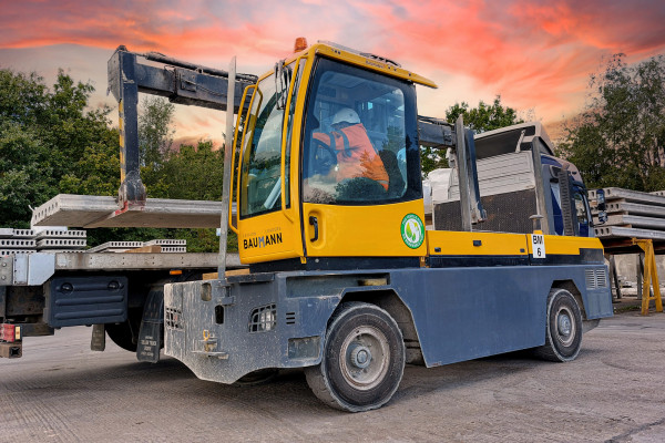 machinery vehicle loading precast concrete Hollowcore beams onto lorry bed with sticker that vehicle runs on HVO bio-fuel