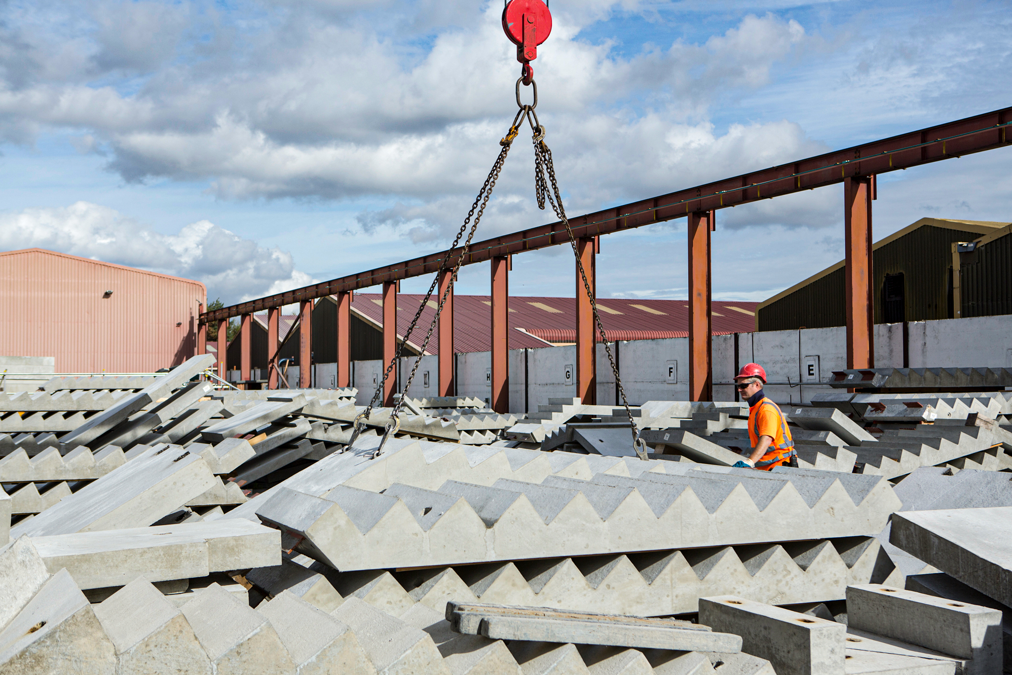 Factory storage yard with precast concrete stairs stacked and an employee managing lift of centre staircase