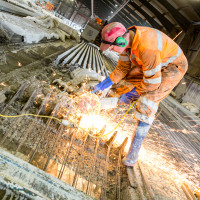 Milbank factory employee uses tools to cut tensile wire in concrete T-beam