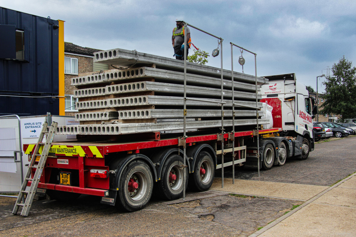 Articulated lorry loaded with Hollowcore slabs with employee on top wearing a high vis vest and hard hat