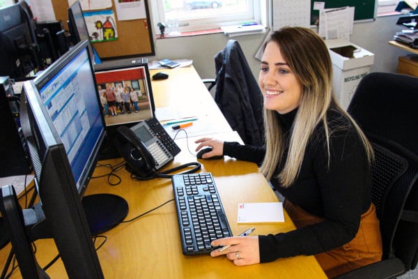 A female sales employee sits at a workstation smiling