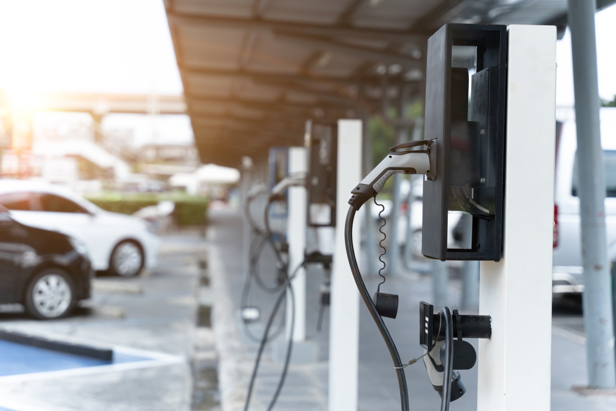 A close up of an EV charger on a white metal post