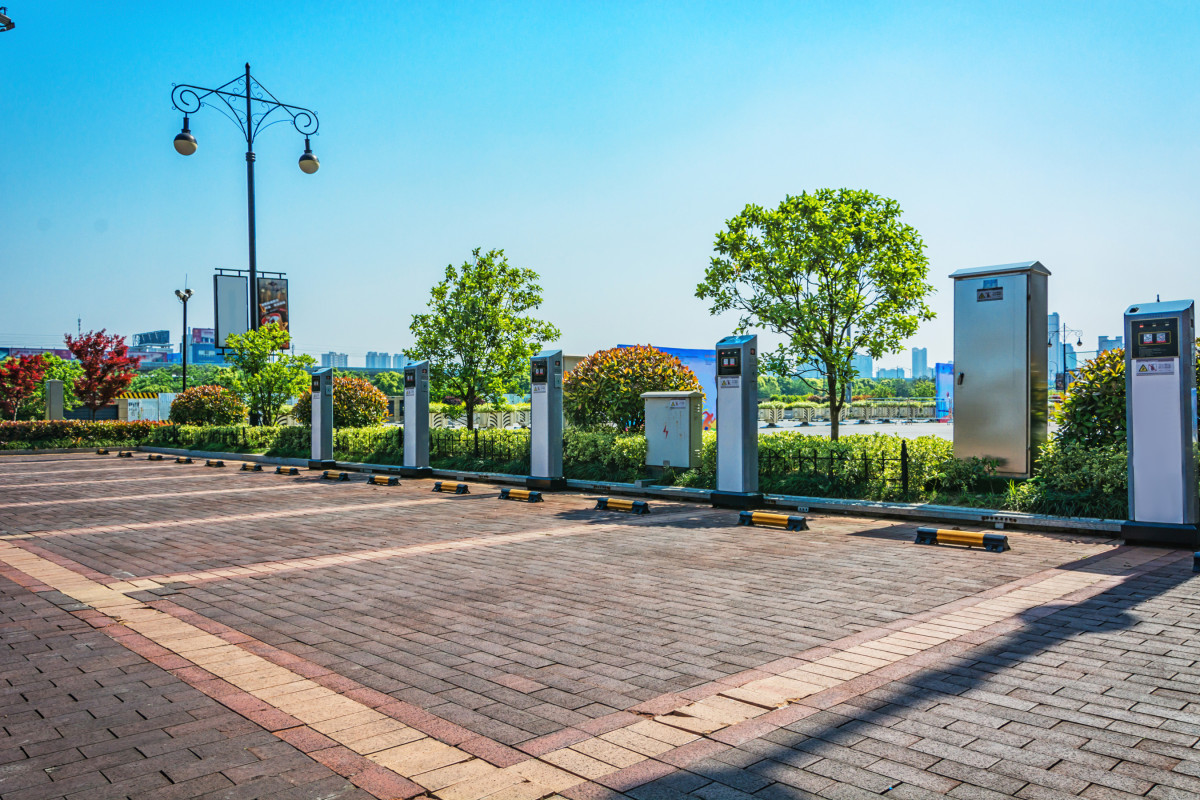 a row of EV chargers sit with a blue sky in the background